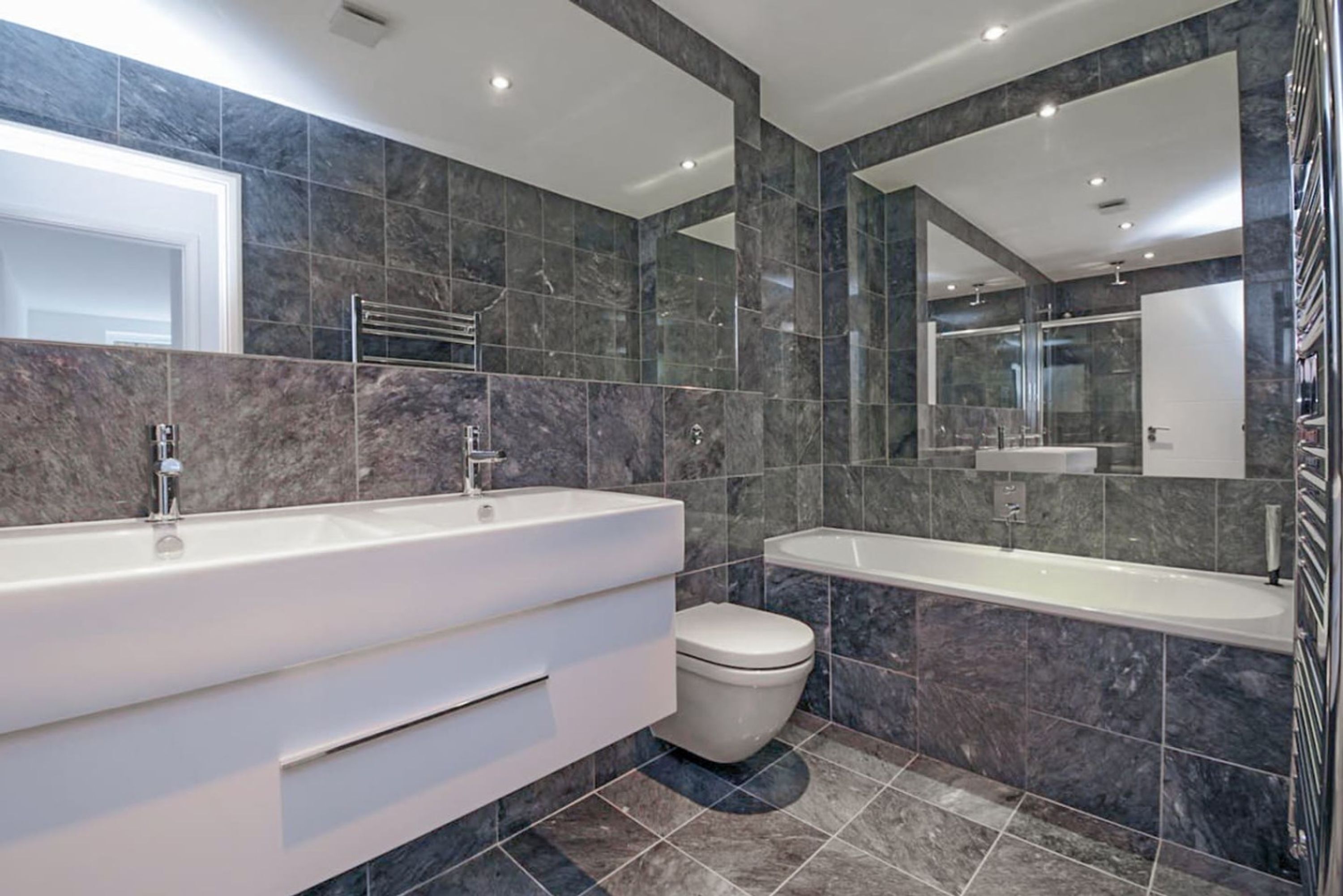 Ein modernes Badezimmer mit einem großen Waschtisch, einer Badewanne und einer Toilette.