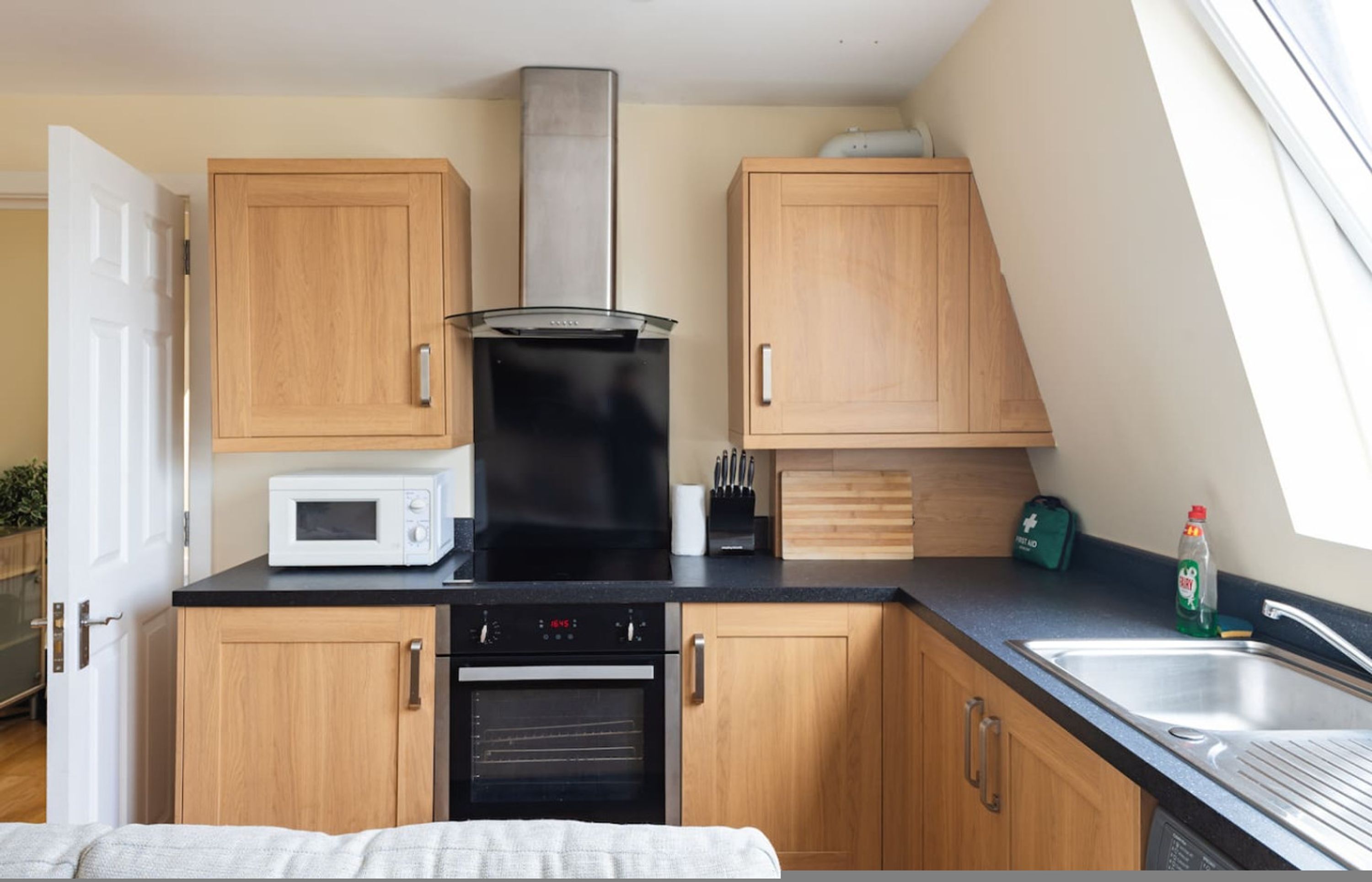 Une cuisine de taille réduite, dotée de meubles en bois, d’un four à micro-ondes, d’une cuisinière et d’un évier.
