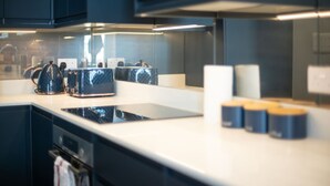 A modern kitchen with dark cabinetry, a white countertop, and a built-in stove. - Trendy Islington Flat Us74 (London)