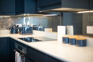 A modern kitchen with dark cabinetry, a white countertop, and a built-in stove. - Trendy Islington Flat Us74 (London)