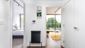 Un corridoio con termosifone, un letto con cuscini e vista su un balcone con tavolo e sedie.