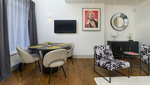 Un soggiorno moderno con un tavolo da pranzo rotondo, due divani, una TV e uno specchio a parete.