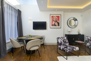 A modern living room with a round dining table, two sofas, a TV, and a mirror on the wall. - Gorgeous Hampstead Home (London)