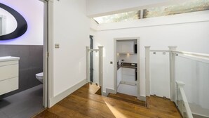 Un interno moderno con una scala in legno, un bagno bianco e un lucernario.
