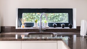 Una cucina con lavello integrato, una finestra sopra al lavello e un piano di lavoro con una pianta e un piccolo vaso.