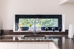 A kitchen with a built-in sink, a window above the sink, and a countertop with a plant and a small vase. - Gorgeous Hampstead Home (London)