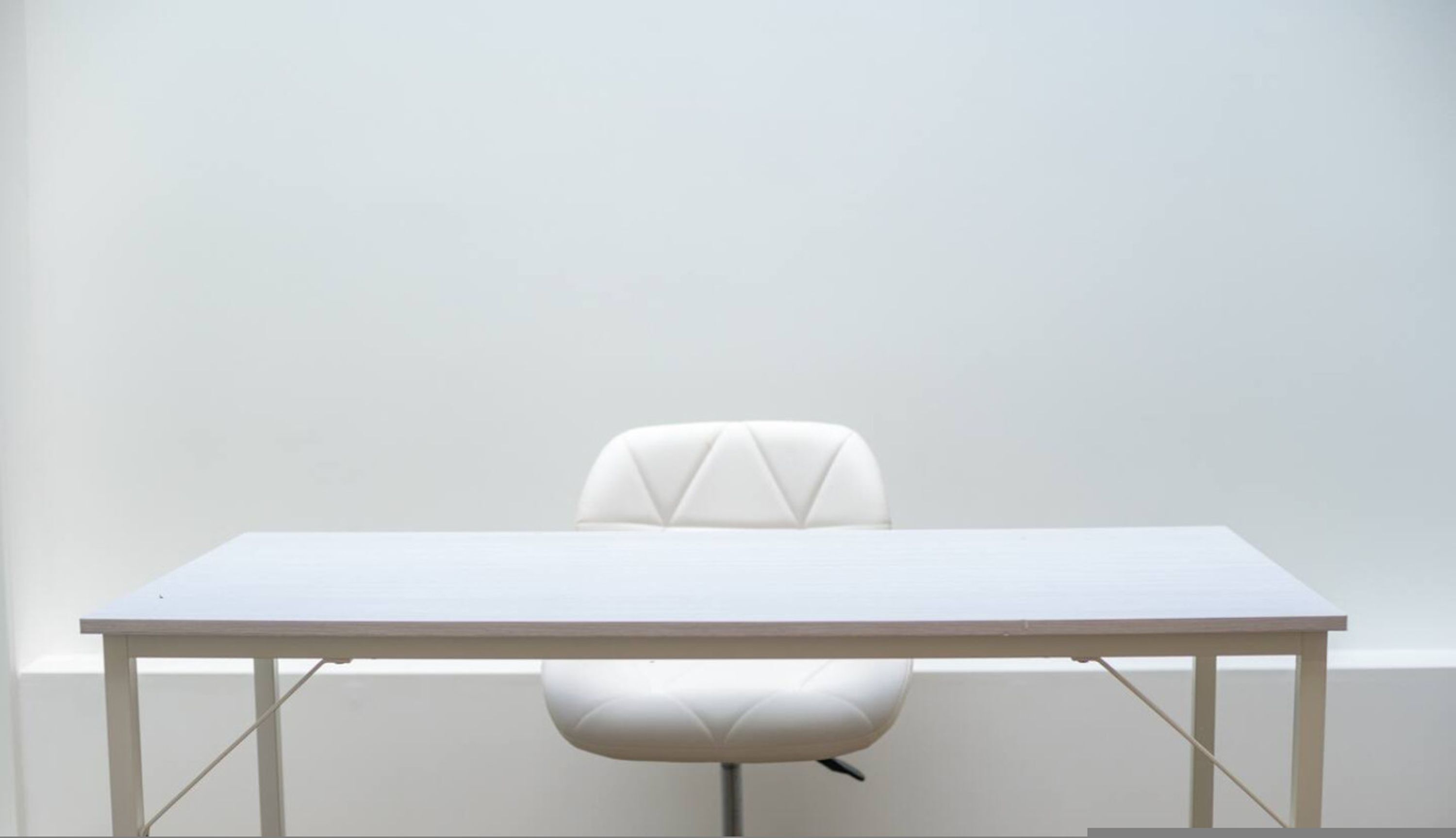 A white table with a chair in front of it.