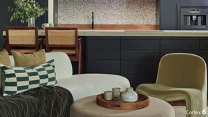Ein modernes Wohnzimmer mit rundem Couchtisch, einer Couch und zwei Sesseln.