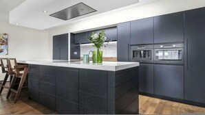 Eine moderne Küche mit dunklen Schränken, einer zentralen Kochinsel und einem eingebauten Backofen.