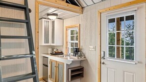 Une cuisine de taille réduite dotée d’un îlot central, de poutres en bois et d’un carrelage à motifs carrés.