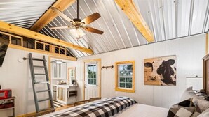 Une chambre à coucher avec un lit, une échelle, un ventilateur de plafond et un tableau accroché au mur.