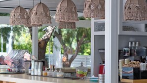 A bar area with macrame pendant lights, a coffee machine, and various glass containers. - PLATY BEACH HOTEL (Lemnos)
