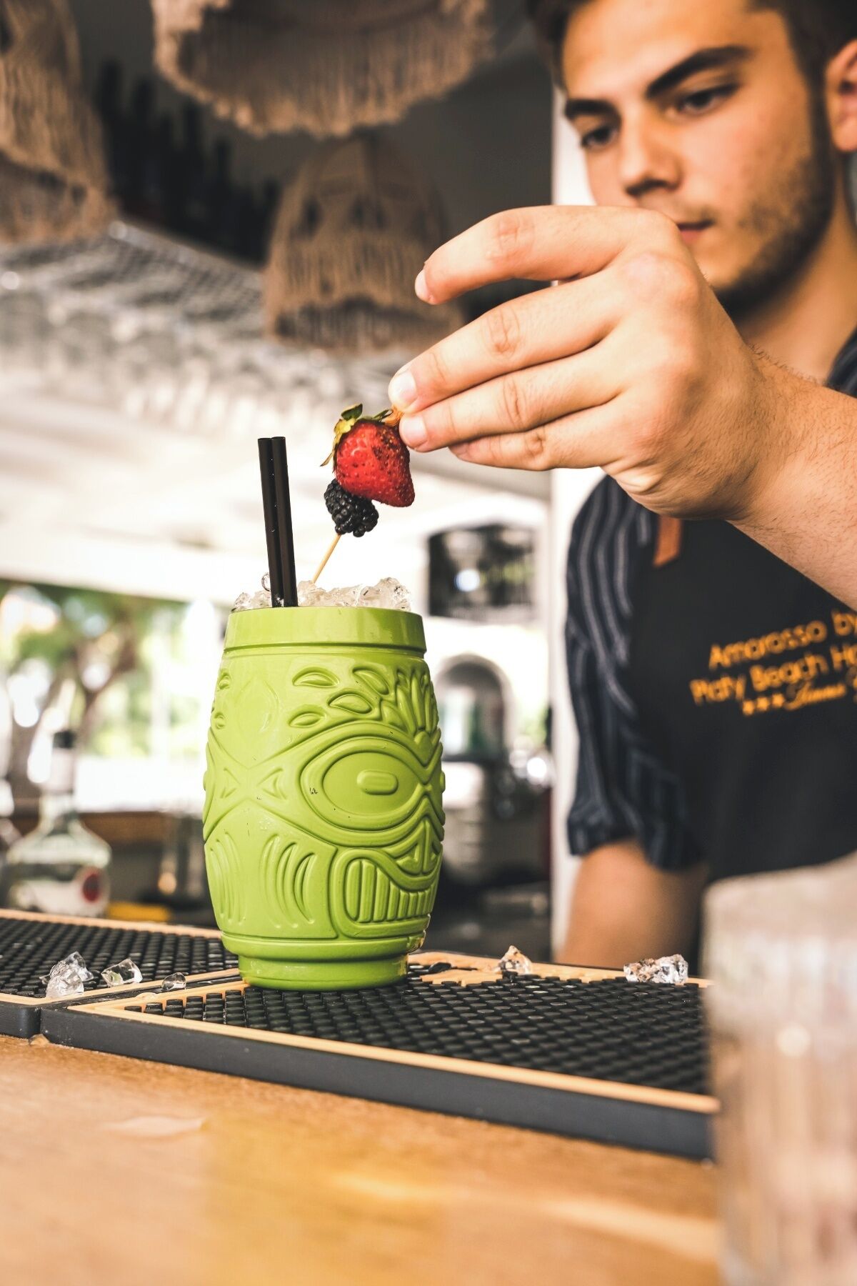 Eine Person hält eine Erdbeere mit einem Getränk in einem grünen Glas.