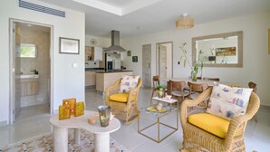 Un vaste espace de vie aménagé avec des meubles en osier, une table à manger et une cuisine en arrière-plan.