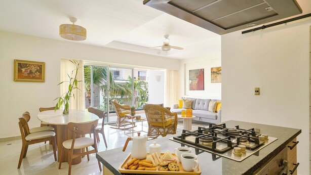 Une cuisine moderne dotée d’un îlot central, d’un coin repas avec des chaises et d’un salon avec un canapé et des fauteuils.
