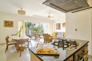 Une cuisine moderne dotée d’un îlot central, d’un coin repas avec des chaises et d’un salon avec un canapé et des fauteuils.