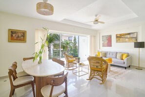 A spacious living area with a dining table, chairs, a sofa, and a floor lamp. - New! Colorful 1BR Apartment in Cap Cana with Balcony (Punta Cana)