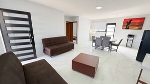 Una sala de estar moderna con un sofá, una mesa de centro y un comedor con sillas y una mesa.