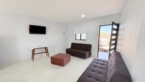 Una sala de estar con sofá, una mesa de centro, televisor y ventana con vista.