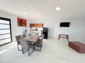 Ein zeitgemäßer Wohnraum mit Essbereich, Küche und Flachbildfernseher.