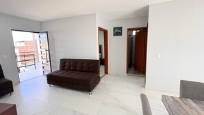 Amplia sala de estar con un sofá marrón, una mesa de centro de madera y vista al exterior a través de un ventanal.