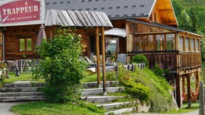 A rustic wooden building with a sign reading "Le Trappeur BAR-RESTAURANT". - Chalet with terrace - 7 guests (Saint-Sorlin-d'Arves)