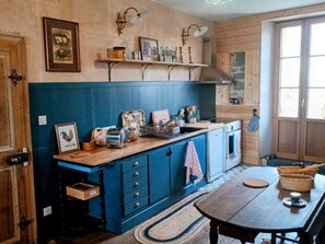 A kitchen with blue cabinets, a wooden countertop, and a dining table with a rug.