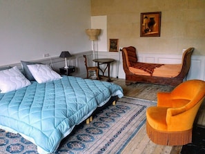 Ein Schlafzimmer mit einem großen Bett, einem kleinen Tisch, einem Stuhl und einem Teppich.