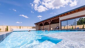 Une piscine dotée d’un espace couvert et de chaises longues.