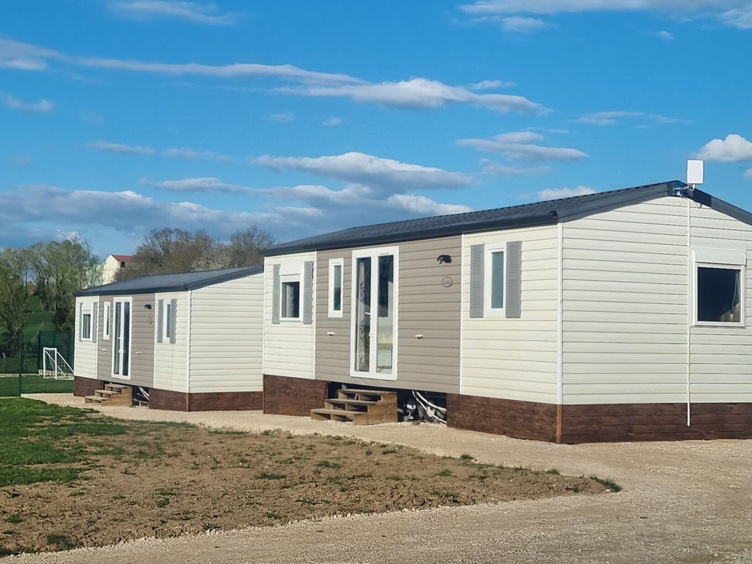 A row of mobile homes with a gravel driveway and a grassy area in front.