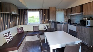Une cuisine moderne avec un coin repas, des placards intégrés et une fenêtre donnant sur un jardin.