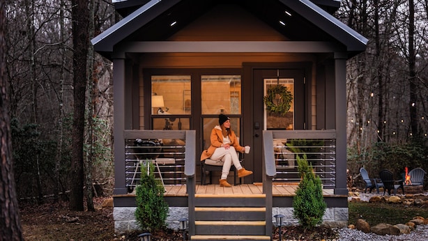 A cozy cabin with a porch, a small staircase, and a fire pit in the yard.
