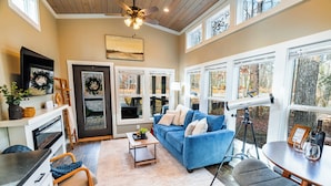 A cozy living room with a blue sofa, a dining table, and a ceiling fan.