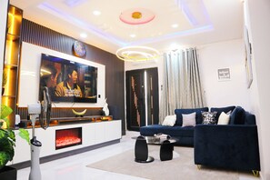 Ein modernes Wohnzimmer mit Flachbildfernseher, einer Couch, einem Couchtisch und einem Kamin.