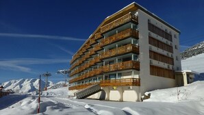 Un hotel de varios pisos con balcones de madera, situado en una zona montañosa nevada.