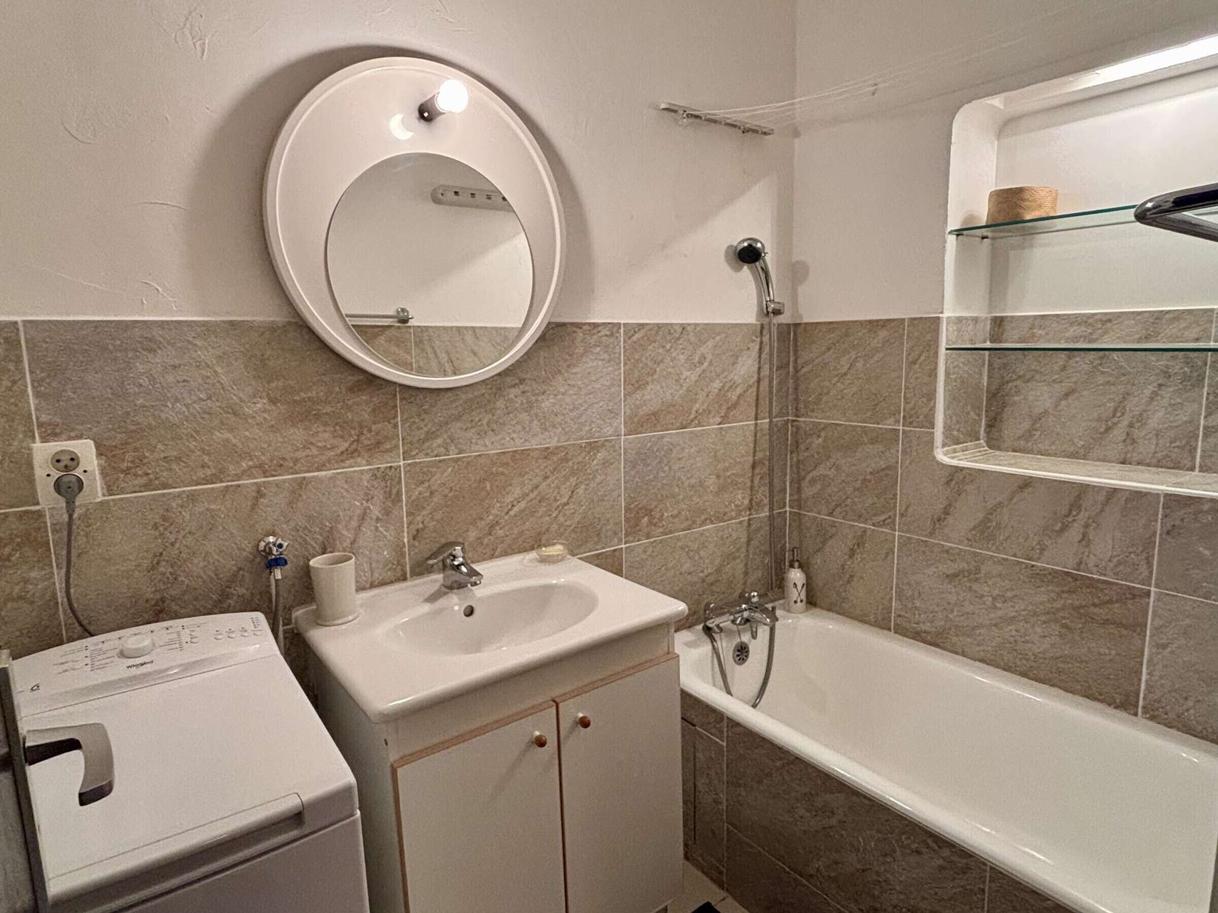 Een badkamer met een wastafel, spiegel en bad.