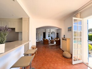 A spacious interior with a kitchen, dining area, and living room, connected by an archway. - Charming house, pool and AC - 10 guests (Port Grimaud)