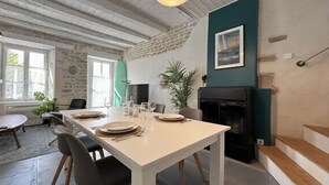 Een eetruimte met een tafel voor vier personen, een open haard en een stenen muur.