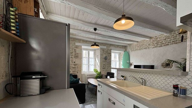 Een moderne keuken met een groot eiland, hangende lampen en een accentmuur van steen.