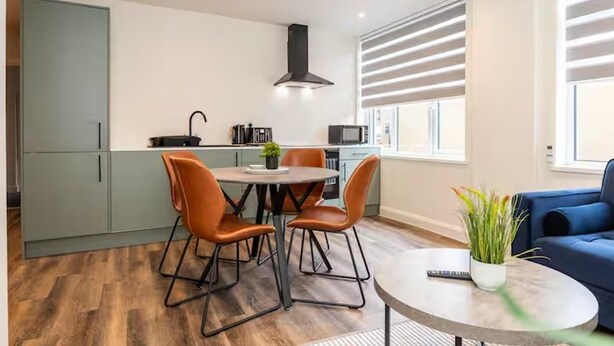 Een moderne keuken met een eethoek, een blauwe bank en een potplant.