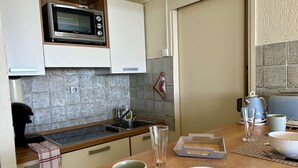 A kitchen with a microwave, sink, and various kitchen items on the counter. - Stunning studio with sea view - 2 guests (Villeneuve-Loubet)