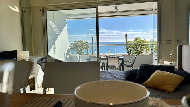 A modern hotel room with a large sliding glass door leading to a balcony with a view of the sea. - Stunning studio with sea view - 2 guests (Villeneuve-Loubet)