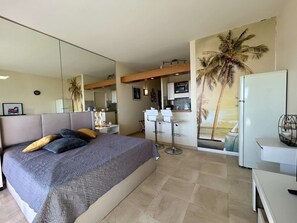 A modern bedroom with a large bed, a desk, and a kitchenette. - Stunning studio with sea view - 2 guests (Villeneuve-Loubet)
