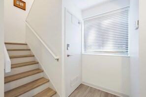 A staircase with wooden steps and white walls, a door with a vent, and a window with blinds. - 2BR Hilton Head Villa | 3 Pools + Bike to Coligny in 5 Min (Hilton Head Island)