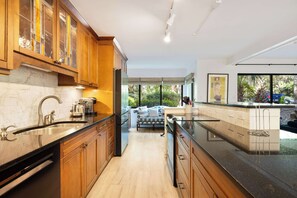 Una cocina moderna con armarios de madera, salpicadero de mármol y una isla grande.