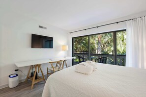 A hotel room with a bed, a desk, a chair, a TV, and a balcony with chairs. - 2BR Hilton Head Villa | 3 Pools + Bike to Coligny in 5 Min (Hilton Head Island)