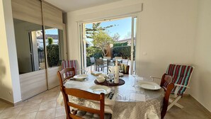 Un coin repas avec une table dressée pour quatre personnes, entourée de chaises dotées de coussins à motifs.