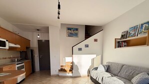 Une cuisine moderne avec des meubles en bois, un four à micro-ondes et une cuisinière. Un escalier mène à une chambre en mezzanine offrant une vue sur la ville.