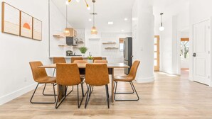 A modern kitchen with a dining area, featuring a central island, pendant lighting, and a view of the outdoors. - The Golden Hour Mirage|Hot Tub|Game Room|Near Park (Joshua Tree)