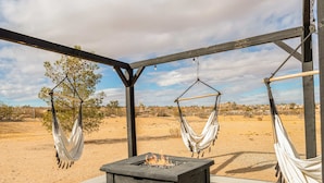 A fire pit under a wooden pergola with two hammocks. - The Golden Hour Mirage|Hot Tub|Game Room|Near Park (Joshua Tree)